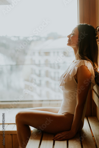 Woman relaxes in wooden sau...