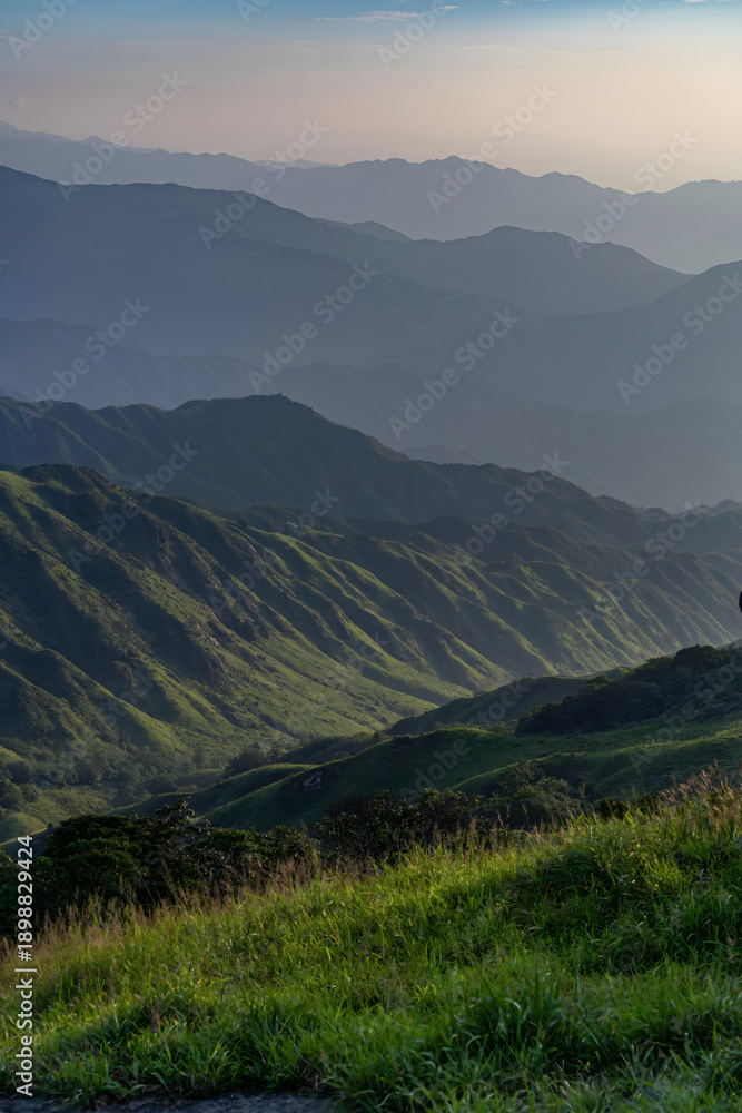 Fototapeta premium Golden Hour Mountain Landscape with Layered Peaks and Verdant Valley