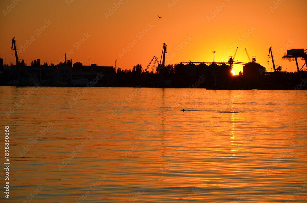 Naklejka premium Industrial port silhouette at dramatic orange sunset