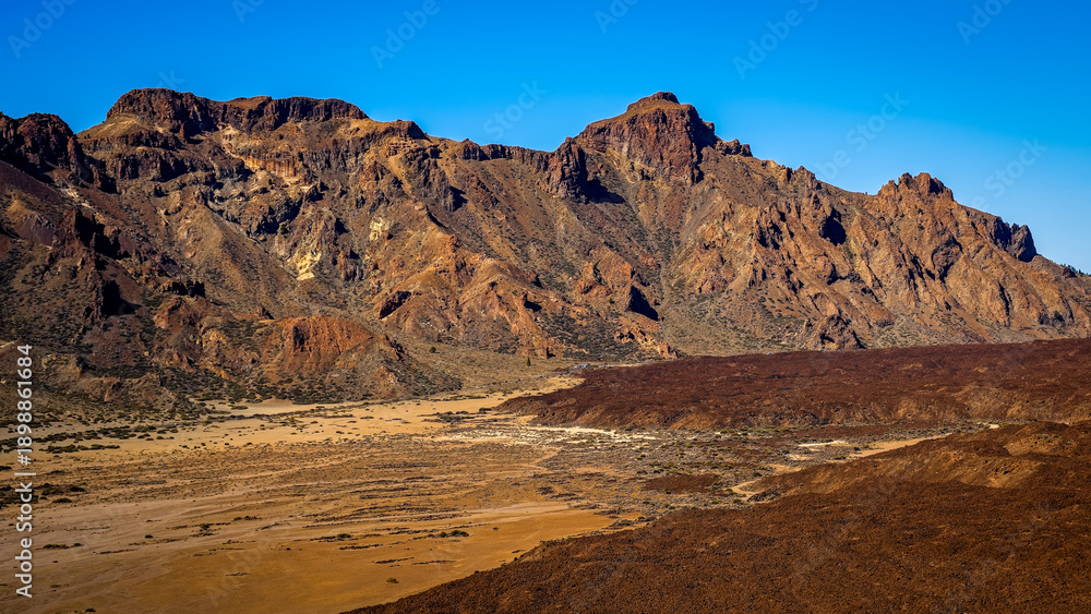 Fototapeta premium Vast volcanic mountain landscape under a clear blue sky with rugged terrain in Teide National Park