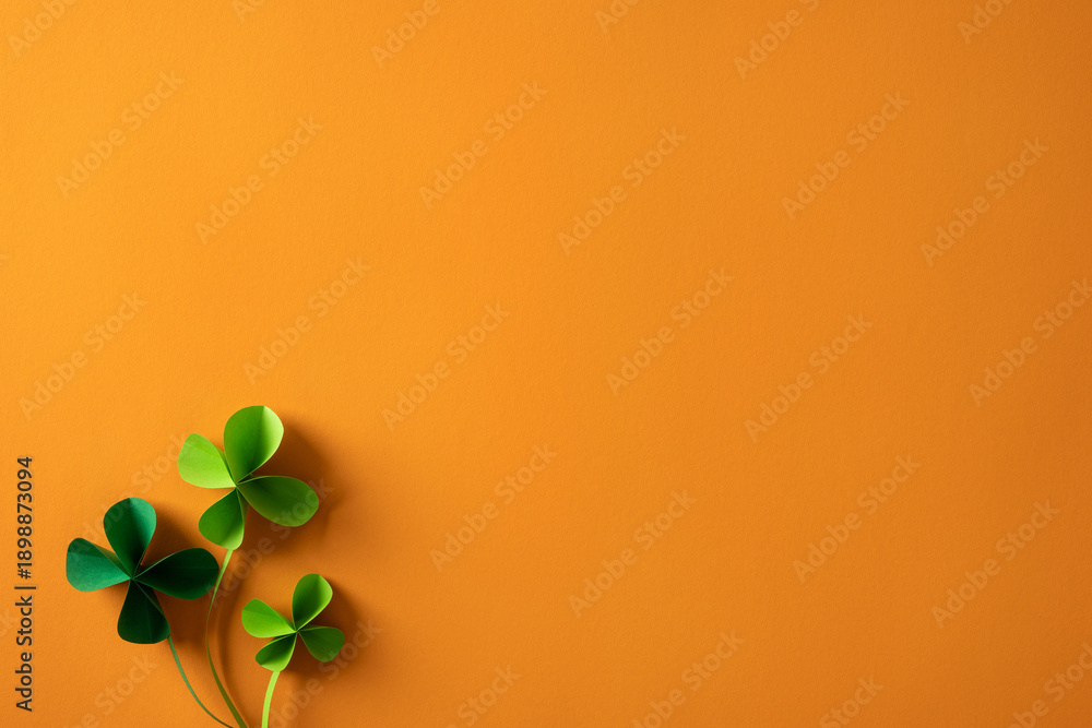 Obraz premium Bright orange background features vivid green shamrocks to convey festive St Patrick's Day mood, perfect for greeting cards, promos, and seasonal content celebrating luck, Irish heritage, and spring