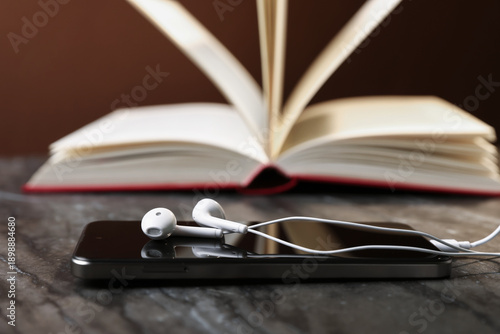 Bild auf Leinwand Smartphone with earphones and book on black table, selective focus