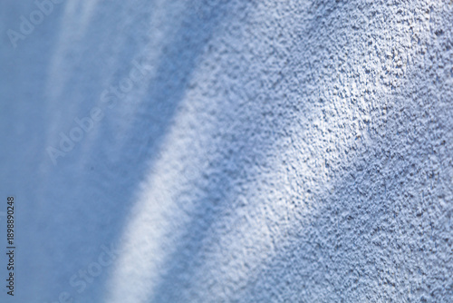 Soft, blurred shadows play across the textured blue wall in soft focus.