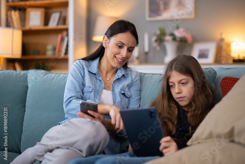 Mother and daughter using tablet and smartphone at home