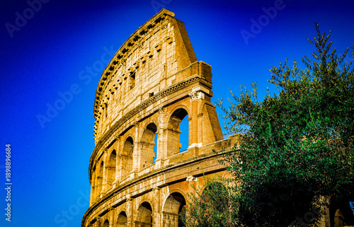 Close-up view of the Colosseum in Rome, Italy — July 20, 2024 — under a deep blue sky, highlighting ancient stone arches and warm golden light. A striking portrait of iconic Roman architecture