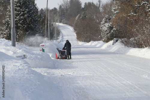 People moving snow after huge snowfall wather event, with snowblower and ATV snowplow
