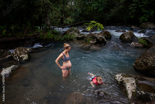 A young boy plays with his pregnant mother in a swimming hole in Costa Rica.