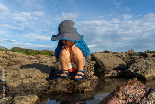 Photography A young boy plays in tide pools at sunset on the coast in Costa Rica