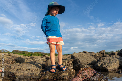 A young boy plays in tide pools at sunset on the coast in Costa Rica.