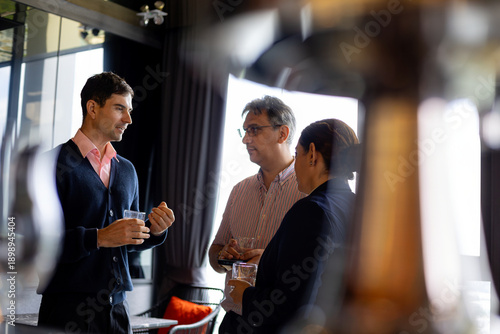 Wallpaper Mural Three business professionals having an informal discussion during a networking break in a modern office, holding glasses of water Torontodigital.ca