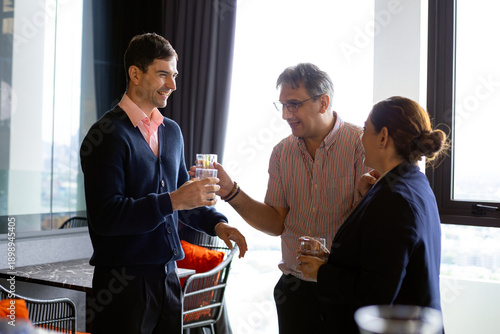 Wallpaper Mural Business professionals smiling and networking during a casual break in a modern office, holding glasses of water, representing workplace communication, teamwork, trust, and positive corporate culture Torontodigital.ca