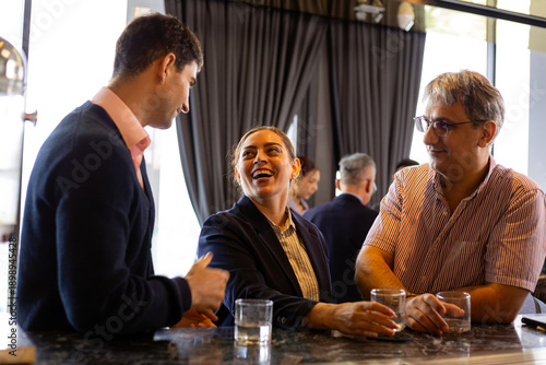 Wallpaper Mural Three business professionals talking and smiling together at modern office counter during networking break, holding glasses of water Torontodigital.ca