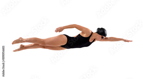 A female swimmer gracefully executing the butterfly stroke in a studio setting. She is wearing a black swimsuit and cap, demonstrating athletic prowess