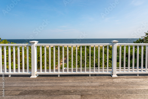 Bild auf Leinwand Ocean view from wooden deck with white railing overlooking coastal dunes and blu