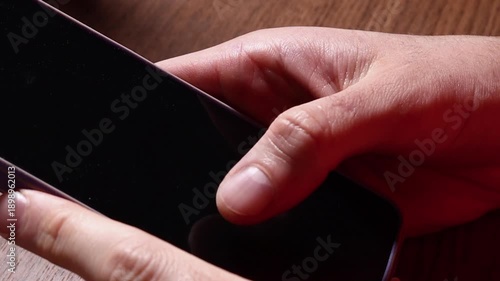 A pair of hands grips a sleek smartphone, fingers poised to tap the screen. The image captures modern mobile use, connectivity, and everyday technology in a bright, clear setting.

