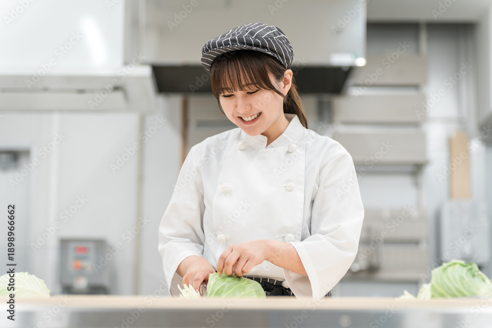 Fototapeta premium A female cook cutting cabbage in the kitchen