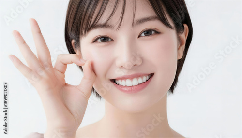 カメラに向かってOKサインをする笑顔の若い日本人女性