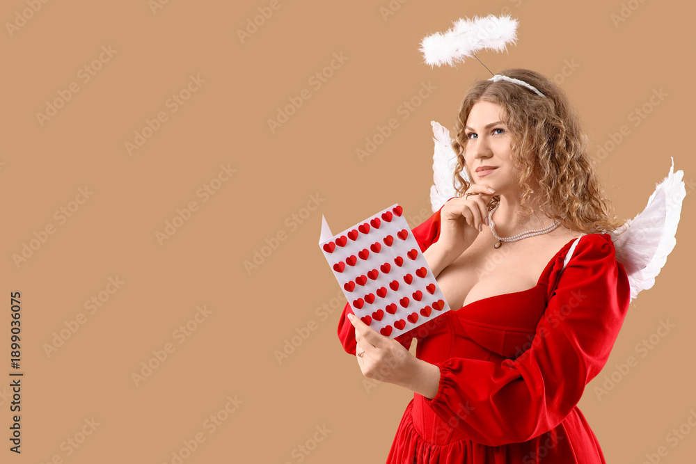 Fototapeta premium Thoughtful young woman dressed as Cupid with card on beige background. Valentine's Day celebration