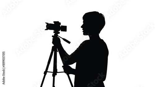Silhouette of a young person adjusting a camera mounted firmly onto a professional sturdy tripod against a bright white background