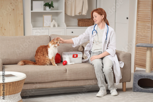 Redhead teenage girl dressed as doctor with cute cat on sofa at home