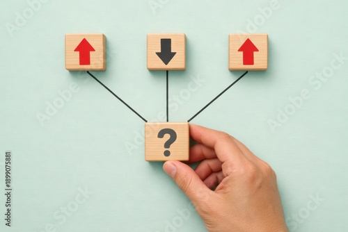 Strategic Choices: A hand navigates a crossroads of options, represented by wooden blocks with arrows pointing up, down, and a question mark, symbolizing decision-making and strategic planning.