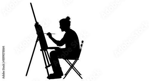 A silhouette of an artist painting on an easel in a studio