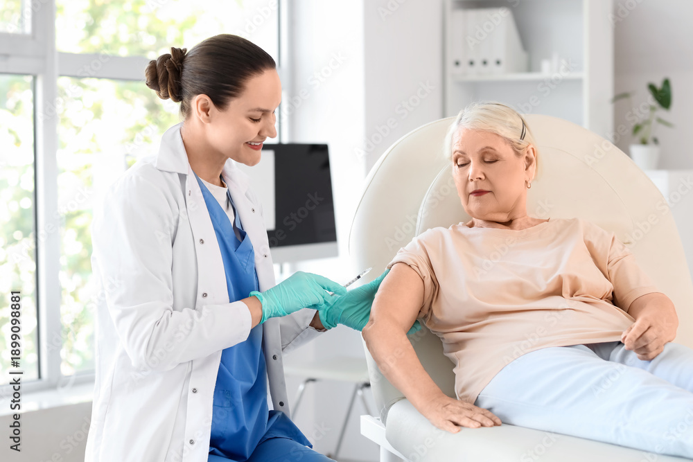 Obraz premium Senior woman receiving vaccine from doctor on couch in clinic