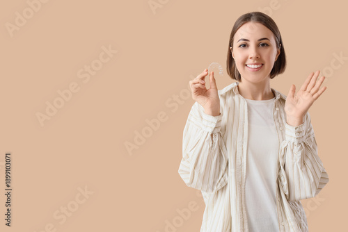 Foto Young woman with occlusal splint showing OK on beige background