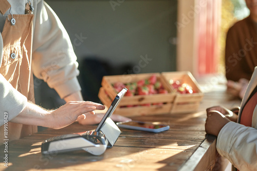 Fotografija Caucasian young adult man operating touchscreen payment terminal while customer