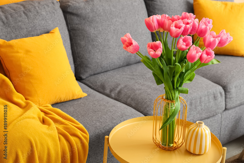 Fototapeta premium Vase with bouquet of beautiful tulip flowers and books on coffee table in living room, closeup