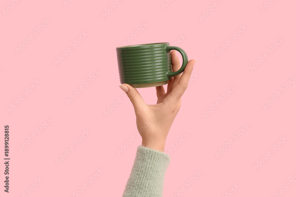 Fototapeta premium Female hand with green ceramic mug on pink background