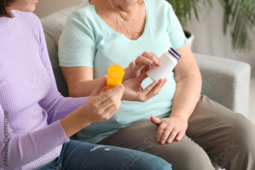 Young nurse giving pills to...