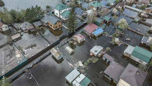Aerial drone footage of a massive city flood with houses and streets submerged under water. Urban flooding caused by extreme weather and heavy rainfall, showing natural disaster impact on residential 