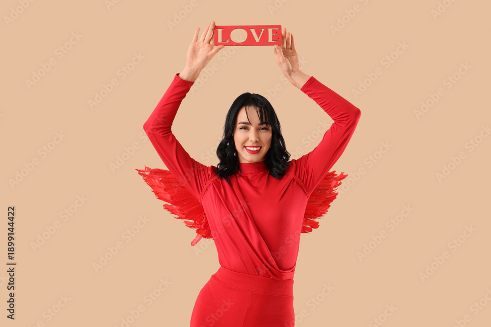 Naklejka premium Beautiful young happy woman dressed as cupid with word LOVE on beige background. Valentine's Day celebration