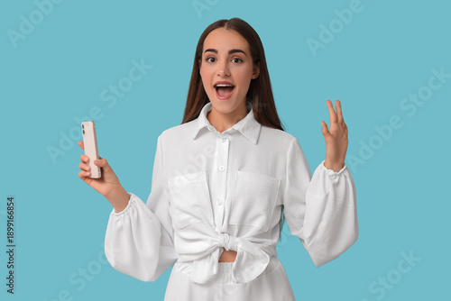 Happy young woman with diastema and mobile phone on blue background