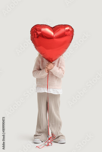 Cute little girl with red heart shaped balloon on white background. Valentines Day celebration