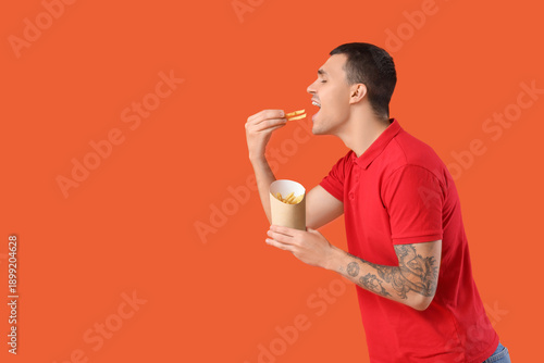Young man eating french fri...