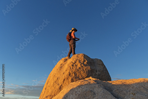 Woman On Top Of A Boulder At Sunset