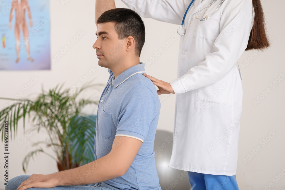 Obraz premium Female doctor checking posture of young man in clinic