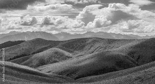 Aerial view of rolling hills and mountains under a cloudy sky in a serene landscape photograph