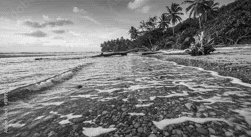 Serene black and white seascape with waves gently lapping against the rocky shoreline