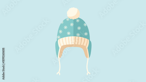 Cozy blue winter beanie hat featuring white snowflake patterns and a fluffy pom pom on a light blue background.