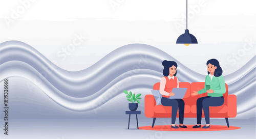 Two women converse while one uses a laptop and the other holds a phone