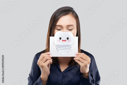 A woman holds a tooth illustration to represent dental implant treatment and modern oral restoration.