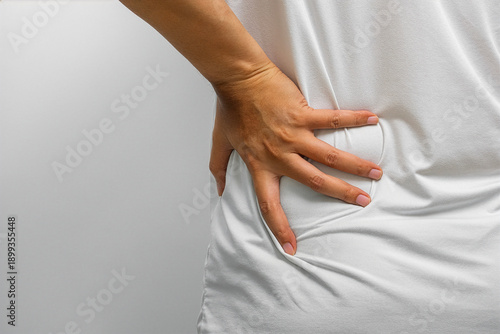 Tableau sur toile Lower back and hip pain with visible discomfort—muscle strain, spinal tension, or nerve pressure requiring physical therapy, orthopedic care, and wellness support