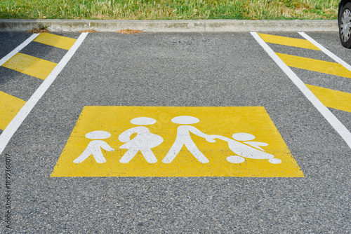 Marquage au sol d'une place de stationnement réservée aux familles, représentant les parents, les enfants dont un en poussette