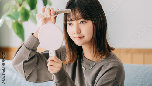 Fotografie 鏡を見ながら前髪を整える日本人女性,室内でのヘアケアと身だしなみ, Japanese woman adjusting her bangs while looki