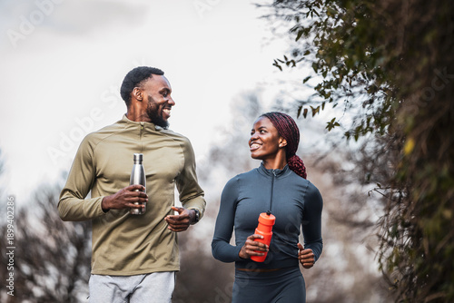 Valokuva African american couple running together outdoors, staying hydrated