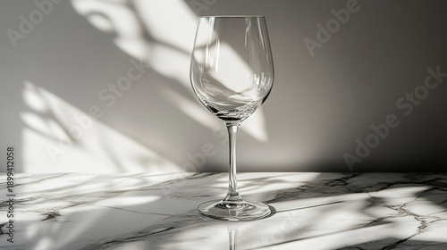 stemware. A crystal-clear wine glass on a marble countertop, reflecting soft light in an elegant minimalist scene. bar promotions.