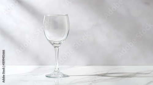 stemware. A crystal-clear wine glass on a marble countertop, reflecting soft light in an elegant minimalist scene. bar promotions.